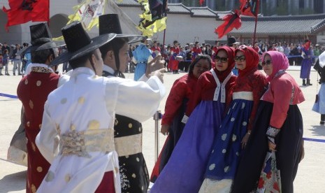 Turis Muslim mengenakan pakaian tradisional Korea, Hanbok, berpose untuk difoto di depan Istana Gyeongbok di Seoul, Korea Selatan, 23 April 2017. 