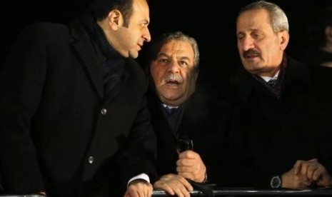 Turkey's European Affairs Minister Egemen Bagis (left), Interior Minister Muammer Guler and Economy Minister Zafer Caglayan (right), chat as they wait for the arrival of Prime Minister Tayyip Erdogan at Esenboga Airport in Ankara December 24, 2013.