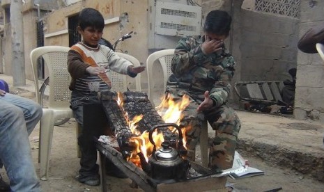 Two boys warm themselves around a fire in Deir Al-Zor, in this picture provided by Shaam News Network and taken January 8, 2013. Picture taken January 8, 2013.