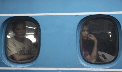 Two Indonesian migrant workers deported from Malaysia watch from a ferry's windows when they arrives at Sri Bintan Pura International Port in Tanjungpinang, Riau Islands. (file photo)