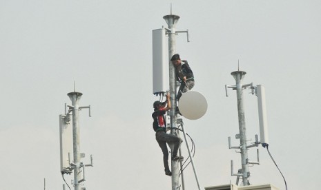 Two techicians install transmitters on the roof of a building in Jakarta. (illustration) 