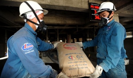 Two workers unload a sack of cement produced by Thang Long Cement plant in Hoanh Bo, Vietnam. PT Semen Gresik has acquire 70 percent shares of Thang Long Cement. Now Sement Gresik rebrands to Semen Indonesia. (illustration)   