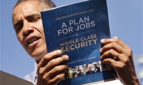 U.S. President Barack Obama holds up his plan for jobs during a campaign rally in Delray, Florida October 23, 2012.   