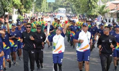 Udjo (kiri) membawa obor Asian Games 2018 saat Torch Relay Asian Games 2018 di Purwakarta, Jumat (10/8).