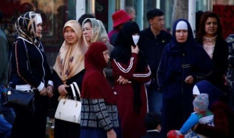 Uighur women stand next to a street to wait for a bus in downtown Urumqi, Xinjiang Uighur Autonomous Region May 1, 2014.