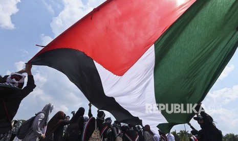 Umat Islam mengibarkan bendera Palestina.