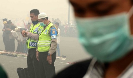 Umat muslim di kota Palembang melaksanakan salat Idul Adha mengenakan masker di Bundaran Air Mancur Masjid Agung SMB II yang diselimuti kabut asap, Palembang, Sumatera Selatan, Kamis (24/9).