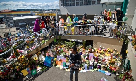 Umat muslim melintasi karangan bunga yang diletakkan warga di depan Masjid Wellington saat pelaksanaan salat Jumat pertama pascapenembakan di dua masjid kota Christchurch pada Jumat (15/3) di Kilbirnie, Wellington, Selandia Baru, Jumat (22/3/2019).