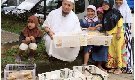 Ustaz Arifin Ilham turut membantu para pedagang cilik menjajakan keripik dan rengginang di depan Masjid Az-Zikra Sentul, Bogor, Jawa Barat.