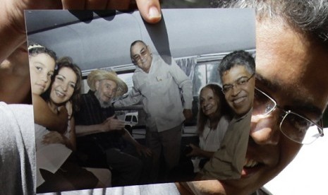 Venezuela's former vice president Elias Jaua shows a picture of himself and former Cuban leader Fidel Castro, (3rd from left), in Havana October 21, 2012. Man in centre of the picture is Hotel Nacional Director Antonio Martinez and woman second from right is Castro's wife Dalia Soto.