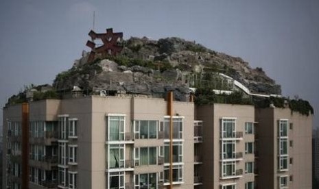 Vila di tengah bebatuan, pepohonan dan semak di atas apartemen setinggi 26 lantai di Beijing, Cina.