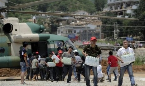 Volunteers deliver bottles of water transported by a helicopter to the earthquake-hit Longtoushan town in Lucian county in southwest China's Yunnan province Wednesday, Aug. 6, 2014. 