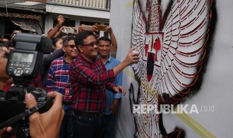 Wagub DKI Djarot Saiful Hidayat menyemprotkan cat untuk menyelesaikan gambar akhir mural di lapangan Kebagusan Dalam IV di Jakarta, Rabu (15/2). 