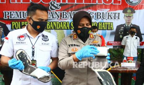 Wakapolres Bandara Soekarno Hatta AKBP Yessi Kurniati (kanan) bersama Kasat Narkoba AKP Rhendy (kiri) menunjukan cara penumpang pesawat menyelundupkan sabu di dalam sandal yang dipakai saat pers rilis di Mapolres Bandara Soekarno Hatta, Tangerang, Banten, Jumat (30/4/2021). Sabu seberat 500gr tersebut dibawa penumpang dari Medan tujuan Lombok yang transit di Jakarta, sebelumnya pelaku sudah dua kali berhasil menyelundupkan sabu dengan modus yang sama ke Lombok.