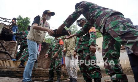 Wakil Bupati Trenggalek Syah M. Natanegara (kiri) bersama TNI dan relawan bencana membersihkan material bangunan rumah warga yang ambruk terdampak gempa di Trenggalek, Jawa Timur, Ahad (11/4/2021). Tercatat sebanyak 63 bangunan di 27 desa 11 kecamatan di daerah tersebut rusak terdampak gempa bermagnitudo 6,7 di Kabupaten Malang. 