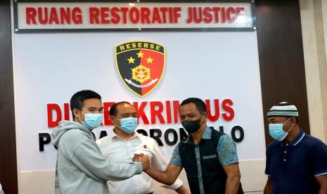 Wakil Direktur Direktorat Reserse Kriminal Khusus (Reskrimsus) Polda Gorontalo AKBP Fammudin (kedua kiri) menyaksikan pelapor dan terlapor berjabat tangan pada pertemuan proses Restorative Justice atau keadilan restoratif di Polda Gorontalo, Kabupaten Gorontalo, Gorontalo, Senin (30/5/2022). Polda Gorontalo menerapkan Restorative Justice dalam kasus dugaan pencemaran nama baik melalui media sosial untuk memberikan kepastian, keadilan dan kebermanfaatan hukum di tengah masyarakat.