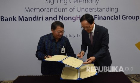 Wakil Direktur Utama Bank Mandiri Sulaiman A Arianto (kiri) dan Chairman & CEO NongHyup Financial Kim Yong Hwan bertukar lembar nota kesepahaman saat penandatangan kerjasama sejumlah bisnis perbankan di Plaza Mandiri, Jakarta (17/7).