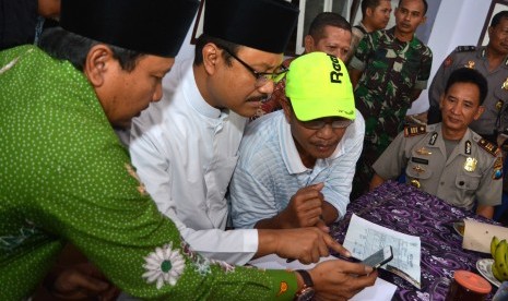 Wakil Gubernur Jawa Timur Saifullah Yusuf (kedua kiri) bersama Bupati Pasuruan Irsyad Yusuf (kiri) berdialog dengan keluarga korban calon jemaah haji yang berangkat lewat Filipina di Balai Desa Bulu Kandang, Prigen, Pasuruan, Jawa Timur, Kamis (25/8).