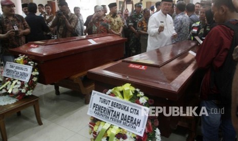 Wakil Gubernur Sumatera Barat Nasrul Abit (kanan) berdiri di antara dua peti jenazah korban kerusuhan Wamena yang telah tiba di Bandara International Minangkabau (BIM), Kabupaten Padang Pariaman, Sumatera Barat, Kamis (26/9/2019).