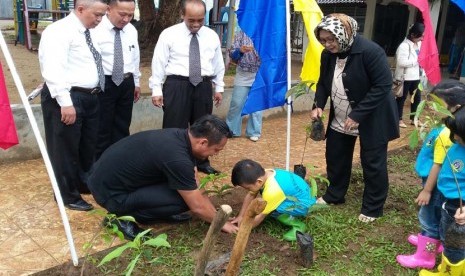 Wakil Ketua DPRD Kota Bogor Heri Cahyono membantu seorang siswa TK Bosowa Bina Insani menanam bibit pohon jambu bol, Senin (25/1), disaksikan direksi Sekolah Bosowa Bina Insani.