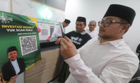 Wakil Ketua PWNU Jatim KH Abdus Salam Shohib (kanan) didampingi Ketua Lembaga Perekonomian Nahdlatul Ulama (LPNU) Kota Kediri Nur Muhyar (kedua kiri), perwakilan PBNU KH Athoillah Anwar Manshur (kedua kanan) memindai QRIS saat peluncuran Baitul Maal Wa Tamwil (BMT) NU di Kota Kediri, Jawa Timur, Jumat (16/9/2022). LPNU berupaya mendorong kemandirian ekonomi umat melalui program Ngaji Preneur sebagai wadah mencetak wirausahawan baru sekaligus menyediakan pembiayaan syariah melalui BMT.