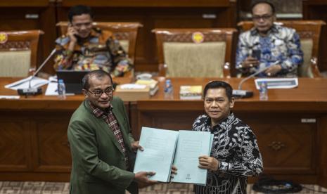 Wakil Menteri Hukum dan HAM Edward Omar Sharif Hiariej (kiri) menyerahkan naskah RUU KUHP dan RUU tentang Permasyarakatan yang telah disempurnakan kepada Wakil Ketua Komisi III DPR Adies Kadir (kanan) dalam rapat kerja bersama Komisi III DPR di Kompleks Parlemen, Senayan, Jakarta, Rabu (6/7/2022). Komisi III dan Pemerintah dalam rapat kerja tersebut bersepakat untuk menyelesaikan Rancangan Undangan-Undangan (RUU) tentang Kitab Undang Hukum Pidana (KUHP) khususnya terkait dengan 14 isu krusial RUU KUHP sebelum diserahkan ke pembicaraan tingkat selanjutnya sesuai dengan mekanisme kententuan perundang-undangan.