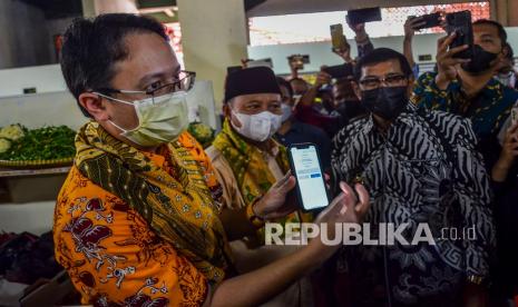 Wakil Menteri Perdagangan Jerry Sambuaga (kiri) didampingi Wakil Gubernur Jawa Barat Uu Ruzhanul Ulum (tengah) dan Wali Kota Tasikmalaya Muhammad Yusuf (kanan) memperlihtakan transaksi Qris di Pasar Rakyat Pancasila, Kota Tasikmalaya, Jawa Barat, Sabtu (22/1/2022). Dalam kunjungannya Jerry Sambuaga meresmikan pasar rakyat Pancasila yang sudah direvitalisasi dari bantuan Pemerintah Provinsi Jawa Barat senilai Rp15 miliar dan sekaligus meninjau harga kebutuhan pokok. 