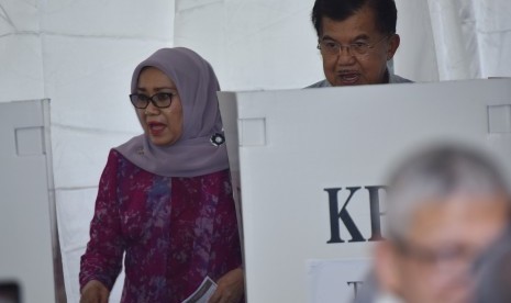 Wakil Presiden Jusuf Kalla (kanan) dan istri Mufidah Jusuf Kalla berada di bilik suara ketika memberikan hak suara pada Pilkada DKI Jakarta di TPS 3 Pulo, Kebayoran Baru, Jakarta, Rabu (15/2).