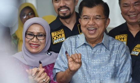 Wakil Presiden Jusuf Kalla (kanan) dan istri Mufidah Jusuf Kalla memperlihatkan jari usai memberikan hak suara pada Pilkada DKI Jakarta di TPS 3 Pulo, Kebayoran Baru, Jakarta, Rabu (15/2). 