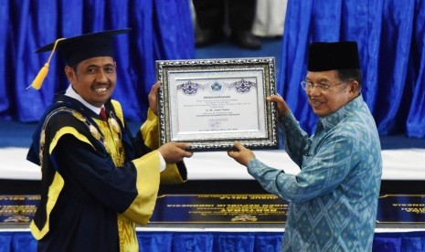 Wakil Presiden Jusuf Kalla (kanan) menerima piagam pengharagaan dari Rektor Universitas Muhammadiyah (Unismuh) Makassar Dr Abd Rahman Rahim (kiri) saat menghadiri Milad ke-54 Unismuh Makassar di Kampus Unismuh Makassar, Sulawesi Selatan, Jumat (28/7). 