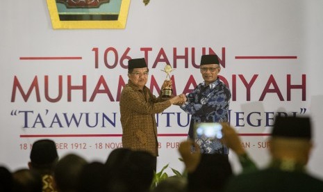 Wakil Presiden Jusuf Kalla (kiri) menerima penghargaan Muhammadiyah Award dari Ketua Umum PP Muhammadiyah Haedar Nashir (kanan) pada acara Milad Muhammadiyah ke-106 di Pura Mangkunegaran, Solo, Jawa Tengah, Ahad (18/11).