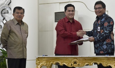 Wakil Presiden Jusuf Kalla (kiri) menyaksikan penandatanganan kerjasama pendanaan Asian Games 2018 oleh Ketua Pelaksana INASGOC Erick Thohir (tengah) dengan Dirut PT Telekomunikasi Indonesia Alex J Sinaga (kanan) di Kantor Wakil Presiden, Jakarta, Rabu (25/10). 