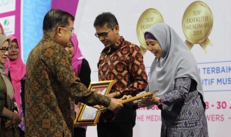 Wakil Presiden Jusuf Kalla menyerahkan penghargaan TOP Eksekutif Muslimah 2019 Bidang Pemerintahan kepada Wakil Gubernur Nusa Tenggara Barat Sitti Rohmi Djalilah di The Media Hotel, Jakarta, Senin (29/7).