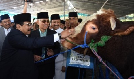 Wakil Presiden RI keenam yang juga Ketua Dewan Pembina Masjid Nasional Al-Akbar Surabaya (MAS), Try Sutrisno (kedua kiri) menerima sapi kurban Presiden RI Joko Widodo dari Gubernur Jawa Timur Soekarwo (kiri) didampingi Wakil Gubernur Jawa Timur Saifullah Y