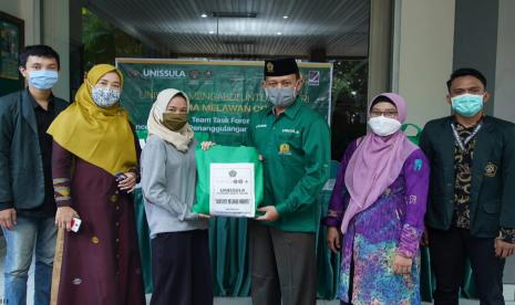 Wakil Rektor III Unissula, Muhammad Qomaruddin ST MSc PhD (berpeci) secara simbolis memberikan bahan makanan sehat kepada mahasiswa yang tidak mudik selama masa darurat Covid-19,