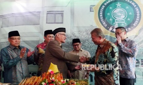 Wakil Rois Aam PBNU Miftahul Akhyar (ketiga kiri) menyerahkan potongan tumpeng kepada Tokoh NU Marzuki Usman (kedua kanan) pada acara peletakan batu pertama pembangunan kampus Universitas Nahdlatul Ulama Indonesia di Jakarta, Rabu (10/8). 