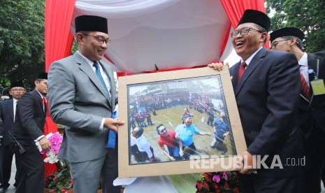 Wali Kota Bandung Oded M Danial (kanan) memberikan foto kenang-kenangan saat lomba makan kerupuk kepada Wali Kota sebelumnya yang saat ini menjabat sebagai Gubernur Jawa Barat Ridwan Kamil (Emil) pada acara serah terima jabatan Wali Kota Bandung, di Plaza Balai Kota, Jumat (21/9).