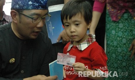 Wali Kota Bandung Ridwan Kamil bersama seorang anak memperlihatkan Kartu Identitas Anak (KTA) pada 