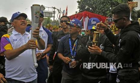 Wali Kota Cilegon Edy Aryadi (kiri) mengangkat obor saat Torch Relay Asian Games 2018 melintasi Kota Cilegon di Cilegon, Banten, Kamis (9/8). 