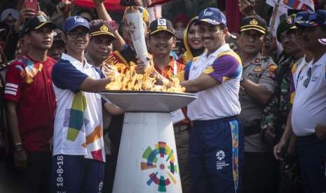 Wali Kota Jakarta Timur M Anwar (kanan) menyerahkan obor Asian Games 2018 kepada atlet Taekwondo Priyaka Ivan Astama (kiri) saat prosesi Torch Relay Asian Games 2018 di kawasan Kramat Jati, Jakarta Timur, Rabu (15/8).