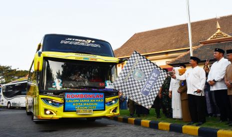 Wali Kota Madiun Maidi (kedua kanan) mengangkat bendera saat memberangkatkan rombongan jamaah calon haji di halaman Wisma Haji Kota Madiun, Jawa Timur, Selasa (7/6/2022). Sebanyak 90 orang jemaah calon haji dari Kota Madiun diberangkatkan menuju Asrama Haji Surabaya dan rencananya diterbangkan ke Tanah Suci pada Kamis (9/6).