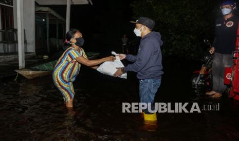 Wali Kota Palangkaraya Fairid Naparin (kanan) memberikan paket sembako kepada warga saat meninjau banjir di Jalan Mendawai, Palangkaraya, Kalimantan Tengah, Selasa (14/9/2021). Fairid Naparin menyalurkan ratusan bantuan paket sembako dan mendata warga yang membutuhkan obat-obatan serta memberi rasa semangat kepada warga terdampak banjir luapan Sungai Kahayan di Palangkaraya sejak Selasa (7/9/2021). 