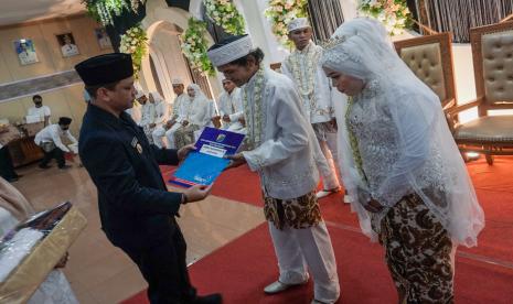 Wali Kota Pekalongan Afzan Arslan Djunaid (kiri) menyerahkan berkas nikah kepada pasangan pengantin saat nikah massal di Pekalongan, Jawa Tengah, Rabu (29/6/2022). Dalam rangka peringatan Hari Keluarga Nasional (Harganas) 2022, Pemerintah Kota Pekalongan memfasilitasi 10 pasang pengantin mengikuti pernikahan massal sehingga status pernikahan pasangan pengantin itu menjadi legal secara hukum dan undang-undang. 