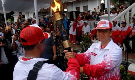 Wali Kota Sukabumi, Mohamad Muraz (kanan) menyerahkan api PON XIX kepada mantan atlet tinju, Veron Matulessy saat Kirab Api PON tiba di Balai Kota Sukabumi, Jawa Barat, Rabu (14/9).