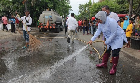 Wali Kota Surabaya Tri Rismaharini (kanan) bersama petugas Dinas Kebersihan dan Ruang Terbuka Hijau (DKRTH) membersihkan jalan di Wonokusumo Kidul, Surabaya, Jawa Timur, Ahad (5/11).