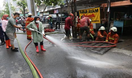 Wali Kota Surabaya Tri Rismaharini (keempat kiri) membersihkan jalan saat kerja bakti pembersihan saluran air di Mulyosari, Surabaya, Jawa Timur.