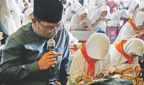 Walikota Bandung, Ridwan Kamil (kiri) memberikan arahan kepada siswa yang mengikuti kegiatan Gerakan Bandung Menulis Alquran di Masjid Agung TSM Bandung, Jawa Barat, Ahad (1/10). 