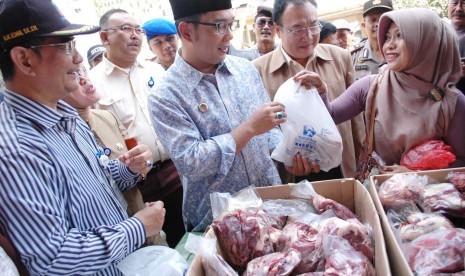 Walikota Bandung Ridwan Kamil melayani pembeli saat sidak Operasi Pasar penjualan daging sapi oleh Bulog, di Pasar Kosambi, kota Bandung, selasa (11/8). Daging sapi dijual Rp 90 ribu per kilogramnya.