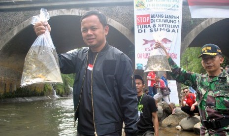 Walikota Bogor Bima Arya (kiri) menebar bibit ikan mata merah di aliran sungai Ciliwung, Kelurahan Sempur, Kota Bogor, Jawa Barat, Minggu (18/12).