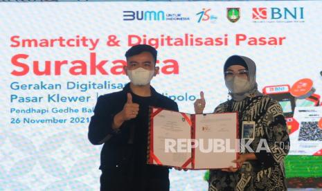 Walikota Solo Gibran Rakabuming Raka (kiri) bersama Wakil Direktur Utama BNI Adi Sulistyowati (kanan) menunjukan Nota Kesepahaman (MoU) Smart City di Balai Kota Solo, Jawa Tengah, Jumat (26/11/2021). Kerjasama MoU dengan Pemerintah Solo tersebut sebagai dukungan BNI terhadap Program Smart City dalam penggunaan fasilitas layanan jasa perbankan yang terintegrasi dengan teknologi informasi tata kelola Kota Solo.